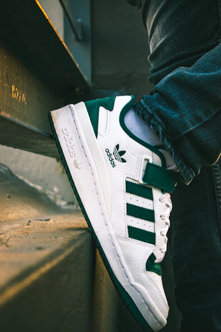 Close-up of a pair of high-end sneakers resting on a concrete ledge with urban graffiti background.