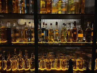 Rows of sparkling spirits bottles lined up neatly, reflecting the warm store lighting.