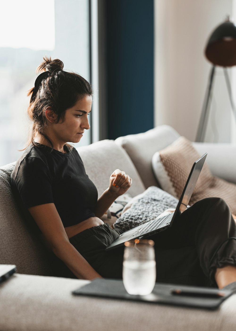 a woman sitting on a couch using a laptop computer