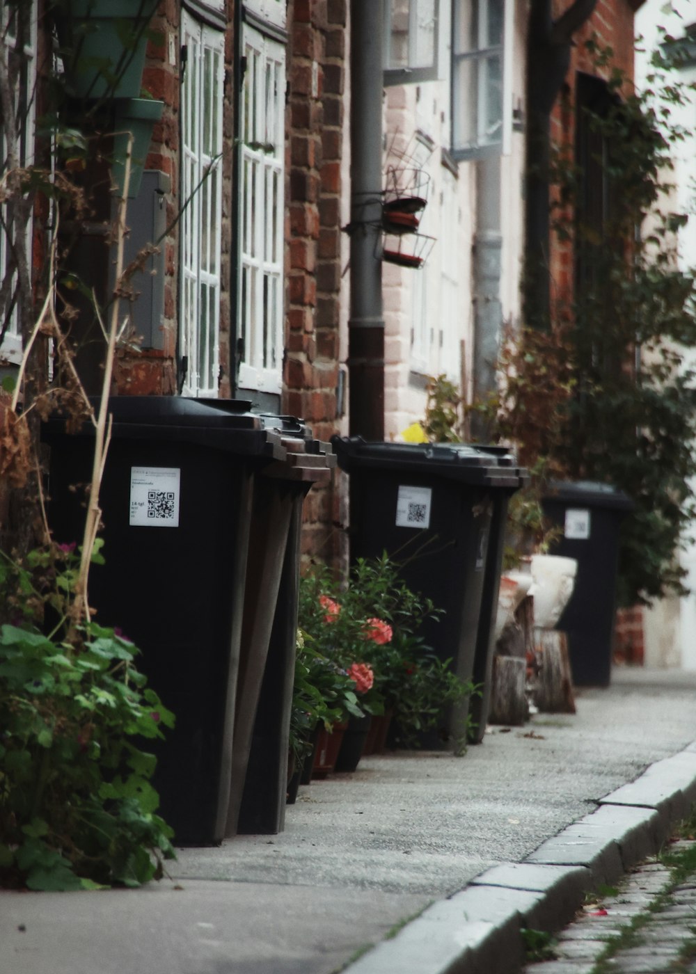 a row of black trash cans sitting on the side of a road