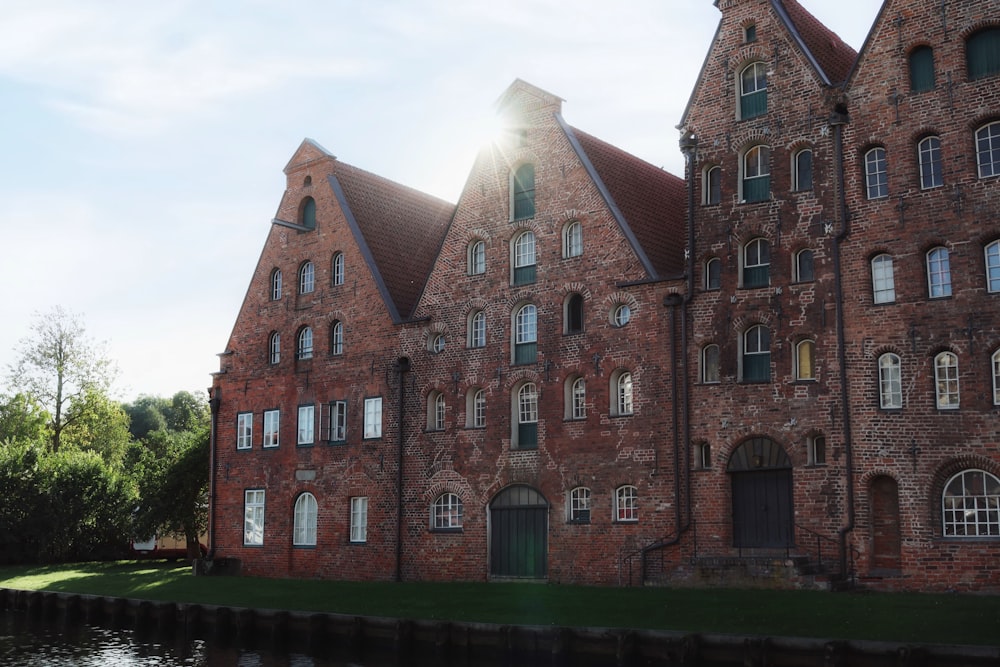 a large brick building with lots of windows next to a body of water