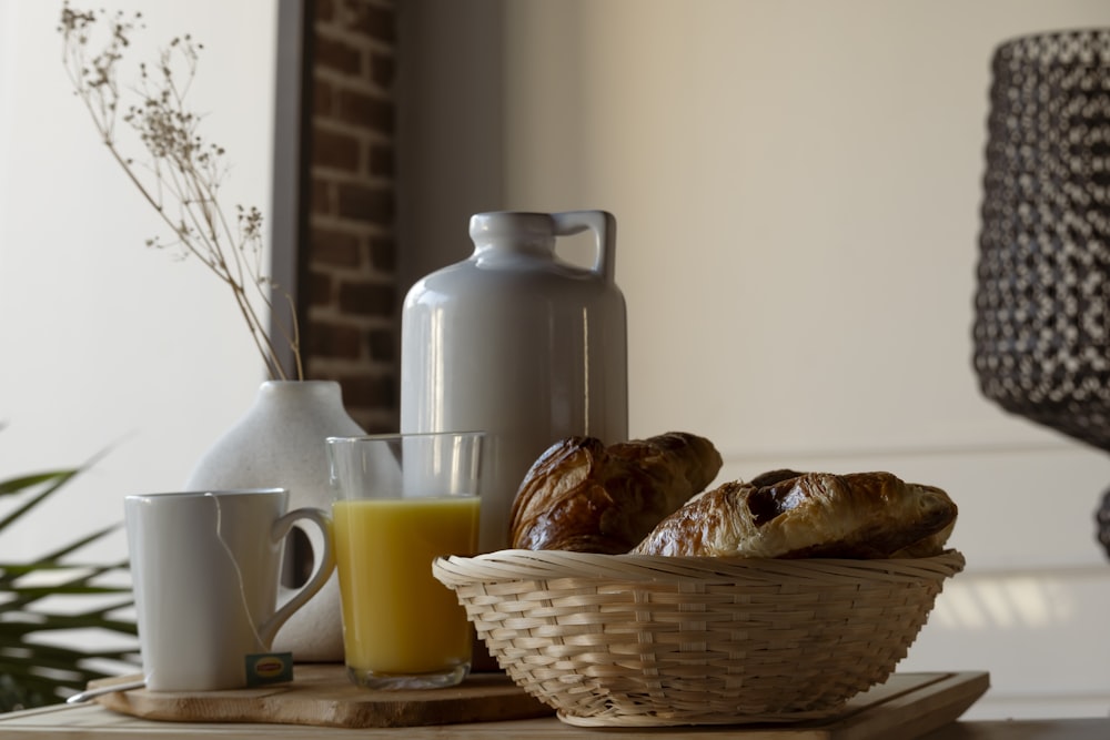 a basket of pastries sitting on a table next to a glass of orange juice