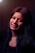 Round avatar of a smiling young woman with short hair, glowing softly against a dark indigo background.