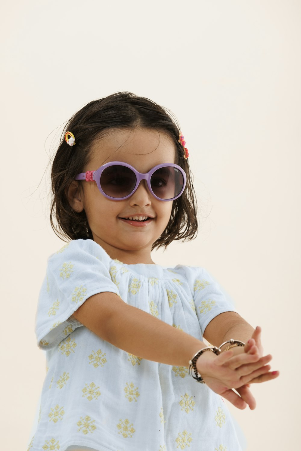 a little girl wearing sunglasses and a bracelet