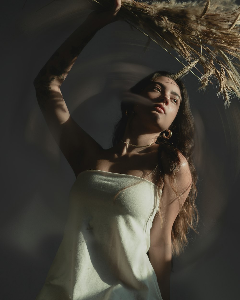 a woman in a white dress holding a stalk of grass