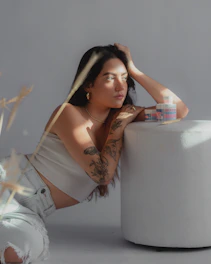 a woman with tattoos leaning on a stool