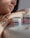 A person with light skin tone, wearing a gold ring, leans on a surface next to two jars of Egyptian Magic all-purpose skin cream. The focus is on the cream and the person's hand, which features a tattoo with delicate linework.
