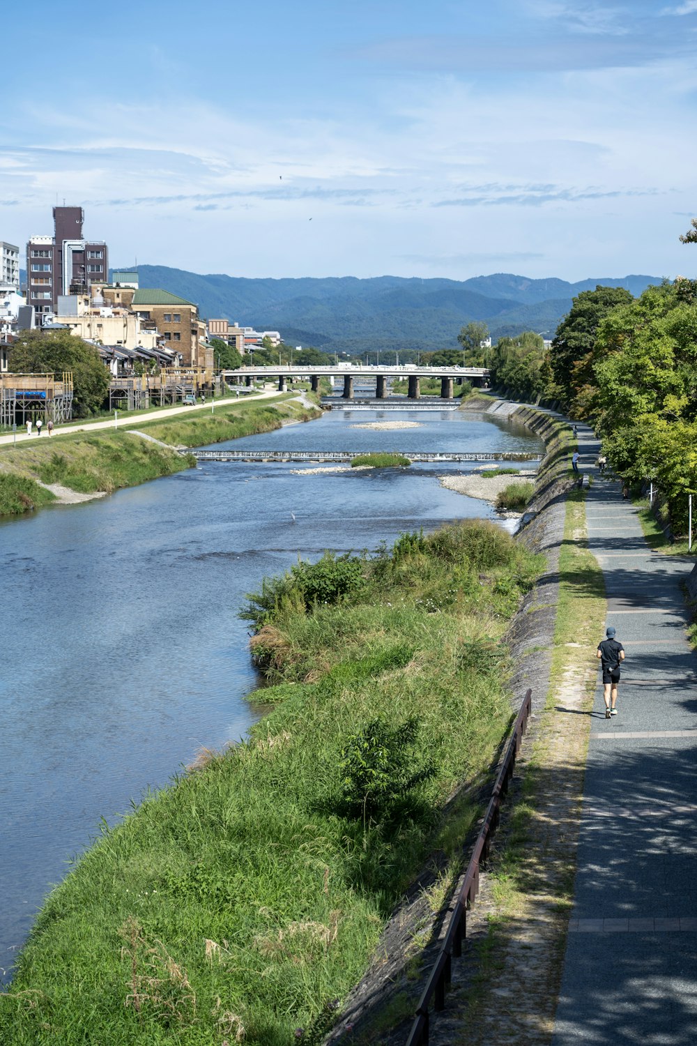川の横の通りを自転車で走る男
