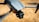 A close-up view of a modern drone capturing detailed design features such as the camera and wing structure. The background is blurred, highlighting the drone's sleek, aerodynamic body.