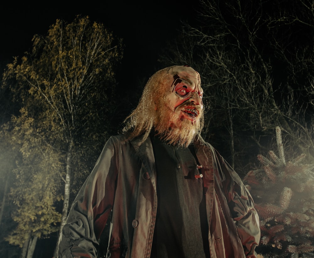 a man with blood on his face standing in the woods