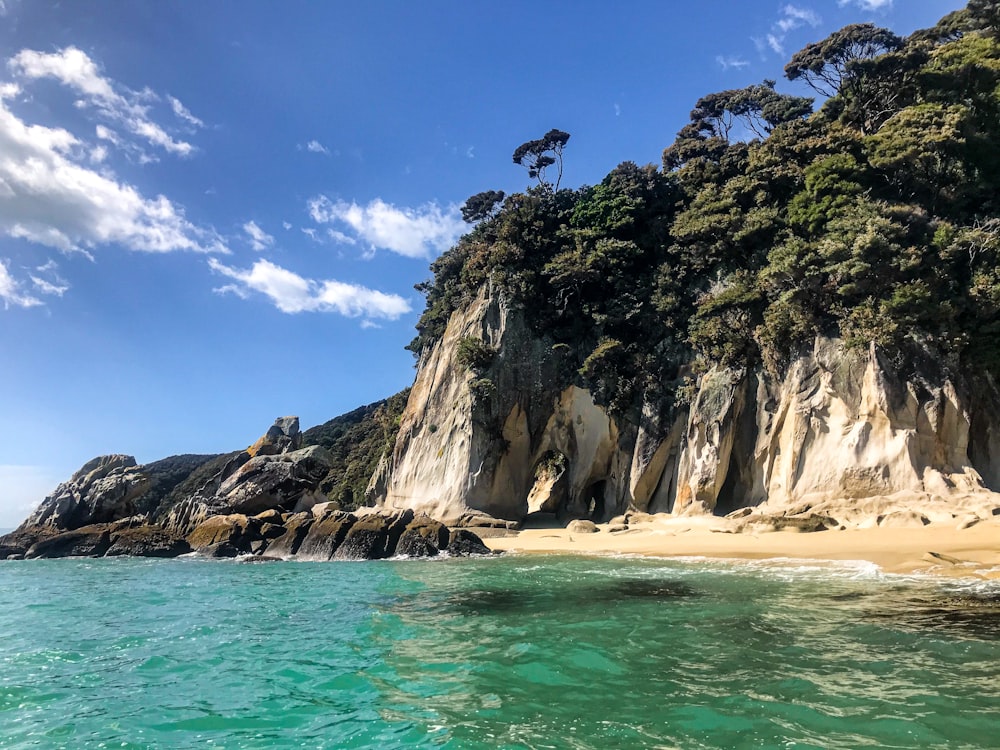 uma praia de areia ao lado de um penhasco rochoso