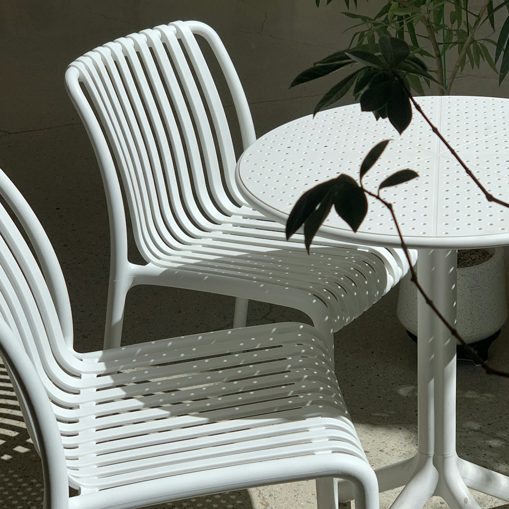 a white table and chairs sitting next to a potted plant