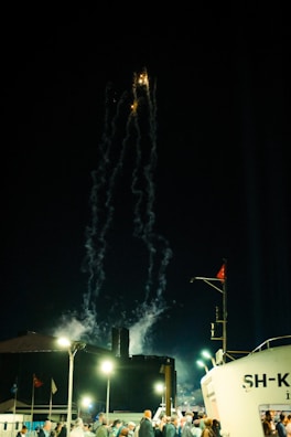 Crowd celebrating with fireworks lighting up the night sky over Olbia harbor