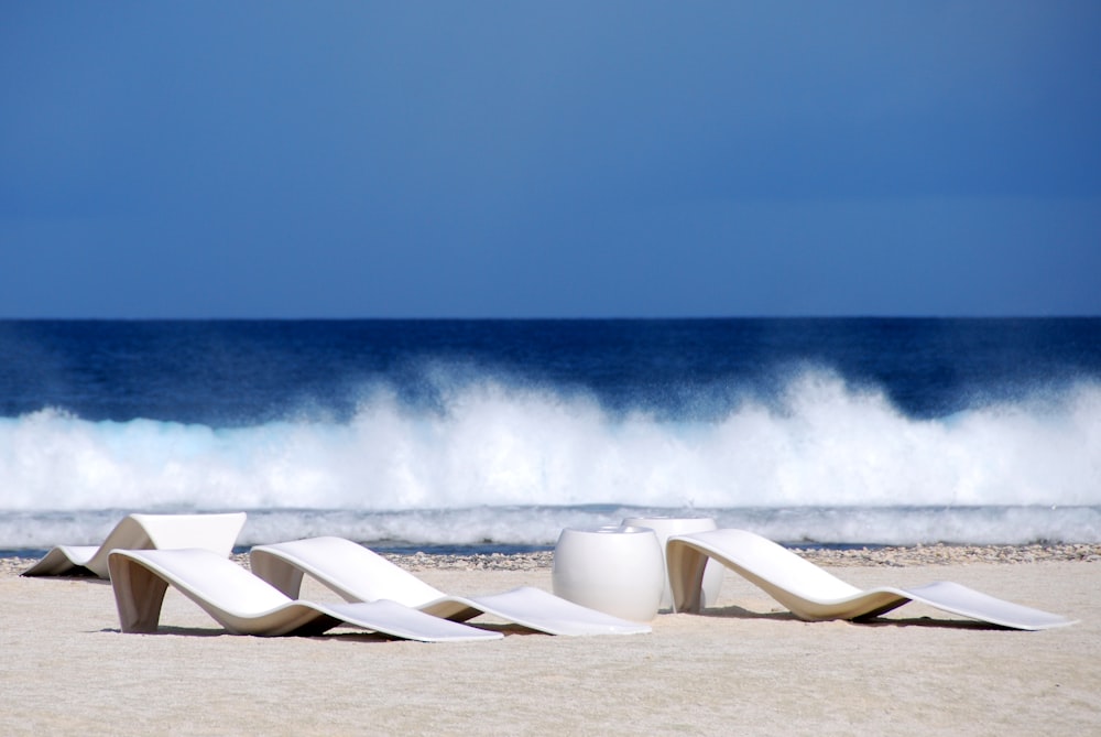 Una fila di sedie bianche sedute in cima a una spiaggia sabbiosa