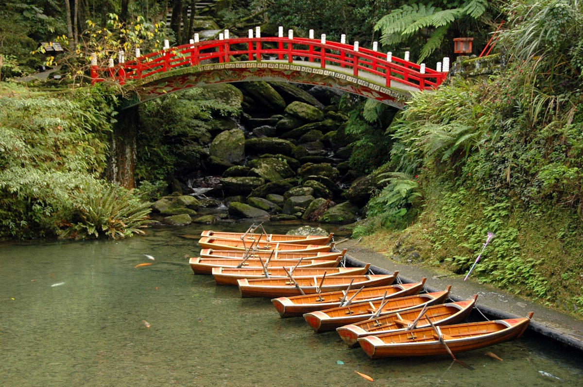 台湾の赤い橋のたもとに係留された木製ボート、水面の倒影が美しい