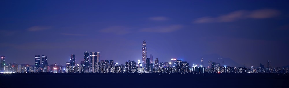 a city skyline at night with a blue sky