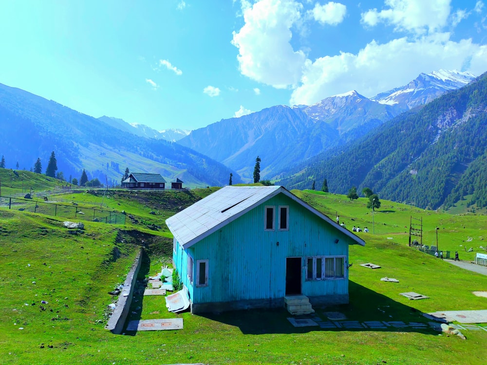 a small blue house sitting on top of a lush green hillside