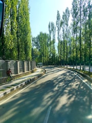 a man riding a bike down a street next to a fence