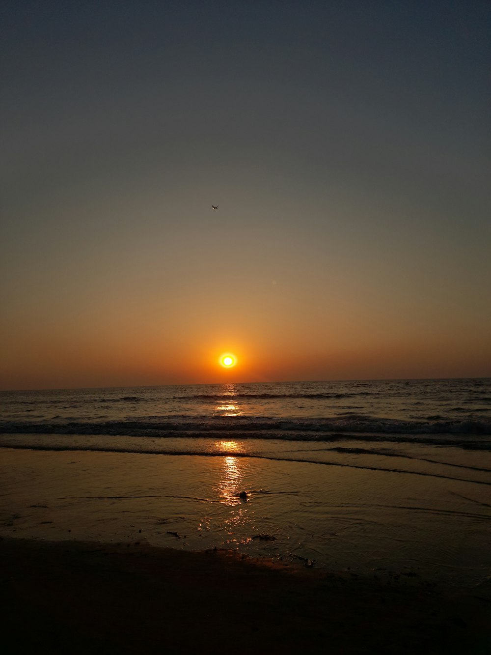 the sun is setting over the ocean on the beach