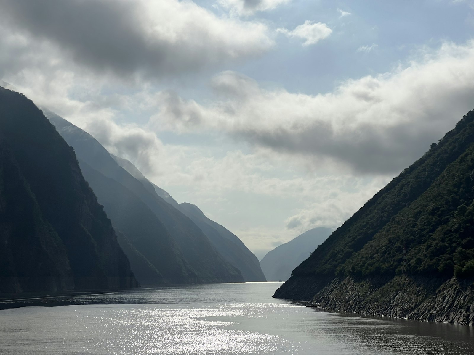 Steep mountainsides of the Wu Gorge rising above the Yangtze River under cloudy skies