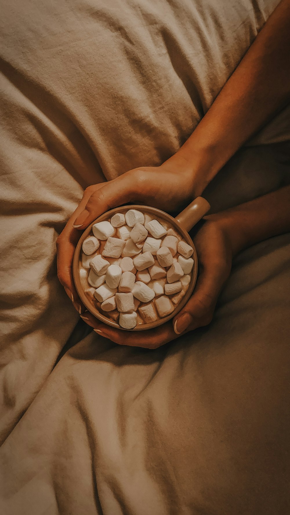 a person holding a bowl of marshmallows on a bed