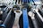 A collection of various wrenches and hand tools neatly arranged on a black perforated surface. The tools are of different sizes and colors, including a prominently visible large blue wrench in the center. The arrangement suggests an organized workspace or tool display.