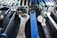 A collection of various wrenches and hand tools neatly arranged on a black perforated surface. The tools are of different sizes and colors, including a prominently visible large blue wrench in the center. The arrangement suggests an organized workspace or tool display.