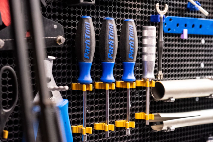 Wall-mounted metal bin racks neatly holding various tools and supplies in a bright garage.
