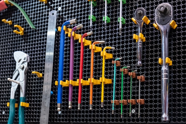 Tools neatly arranged on a black pegboard with yellow hooks, ready for the next repair job.