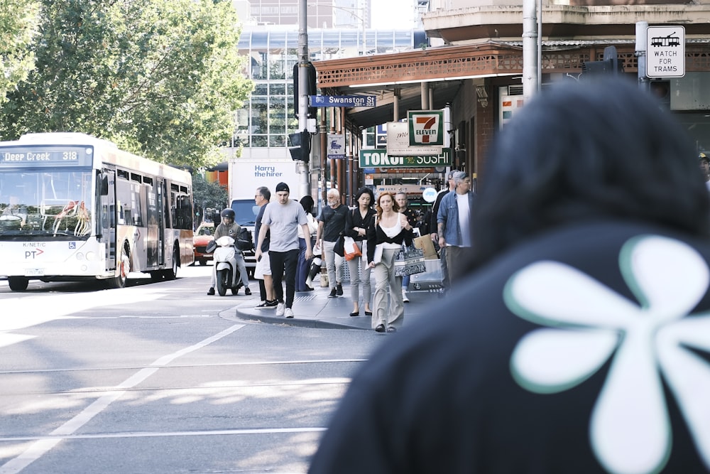 a group of people walking down a street next to a bus