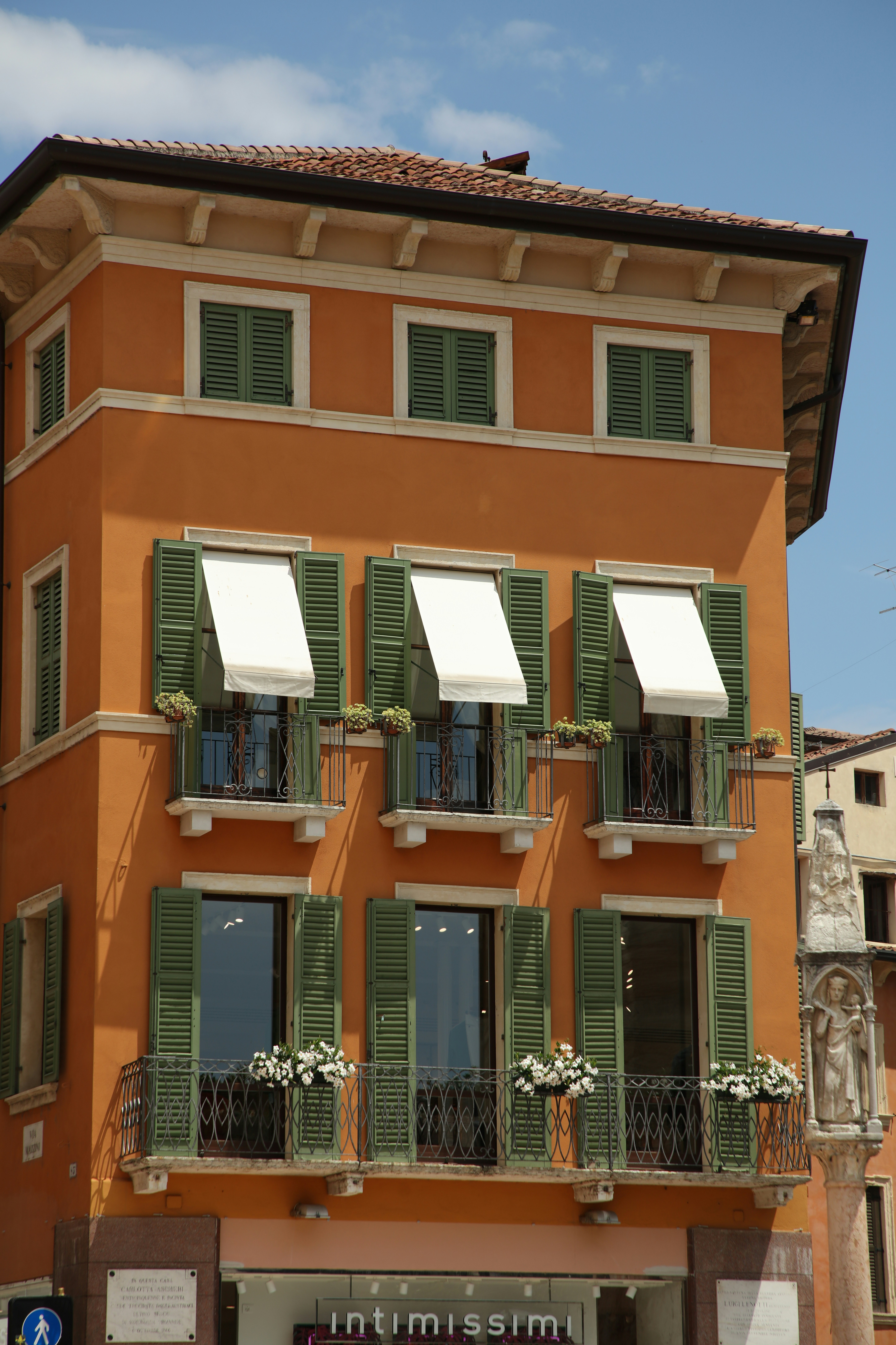 a tall orange building with green shutters and balconies