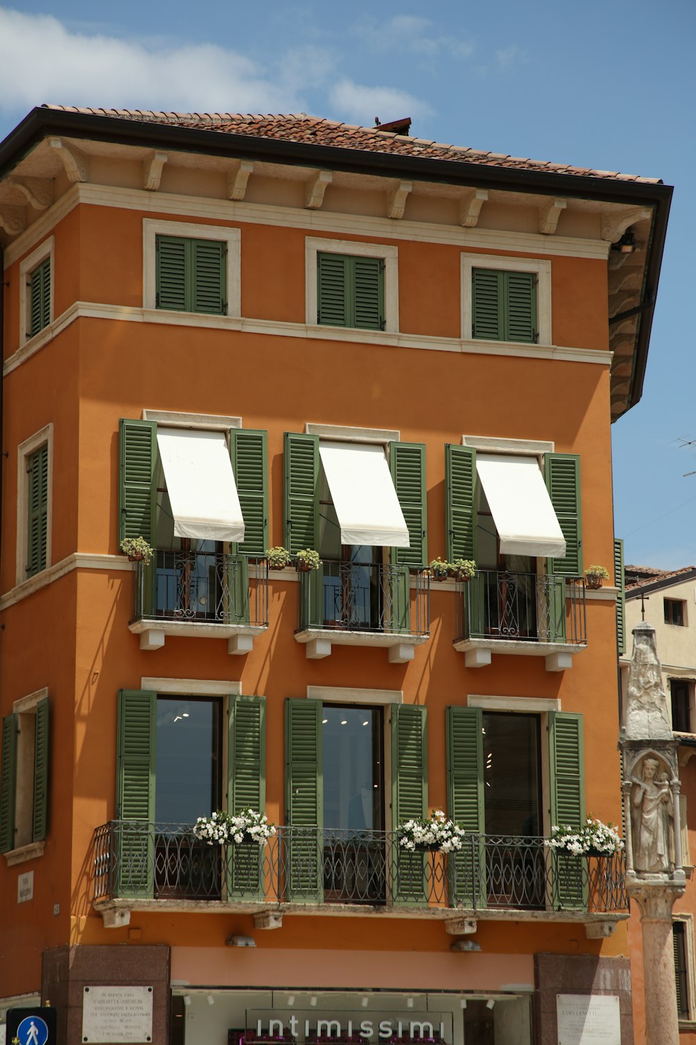 a tall orange building with green shutters and balconies