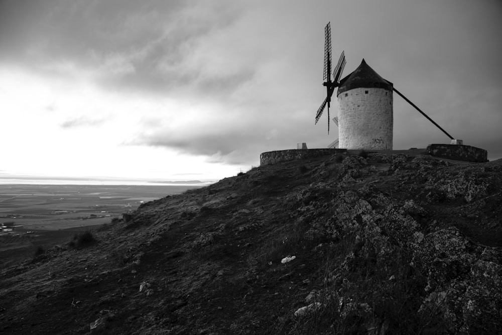 a black and white photo of a windmill on a hill