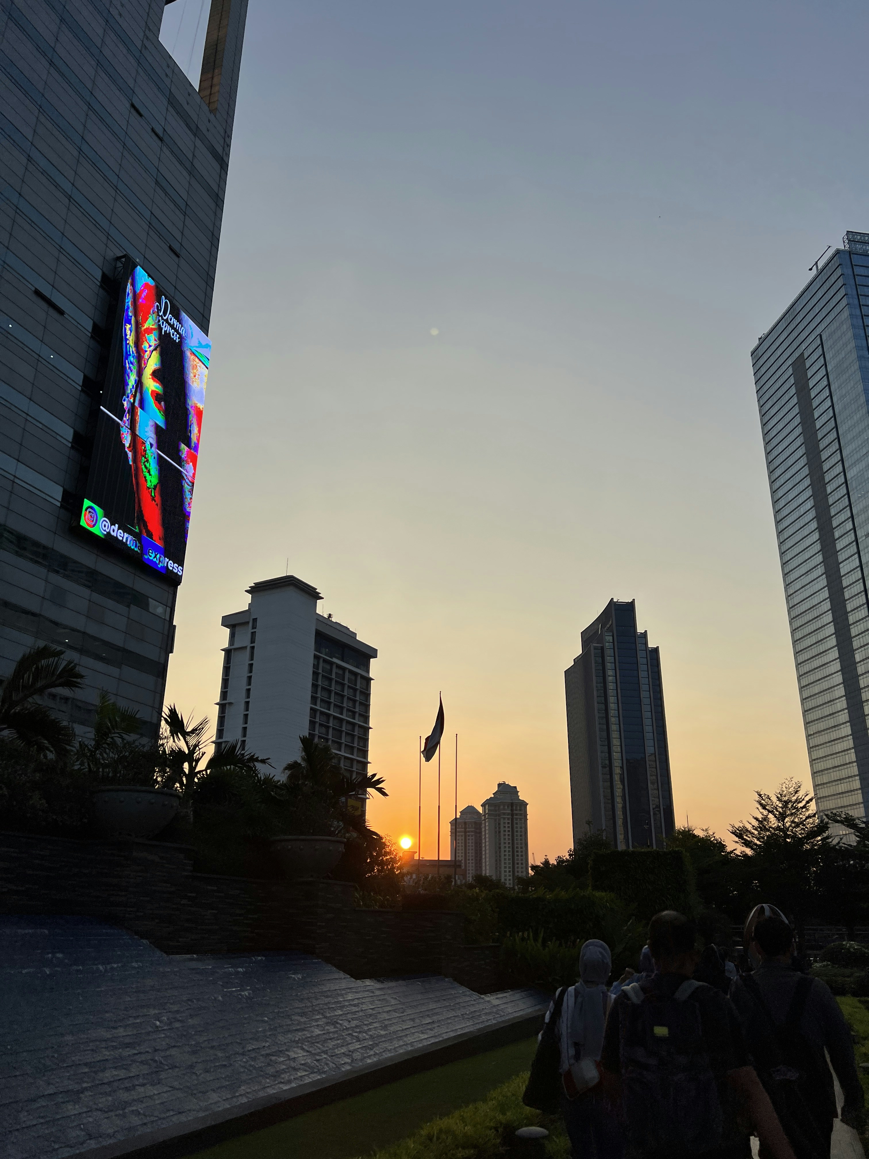 Modern city billboard screen with digital display glowing brightly against dark evening sky cityscape background