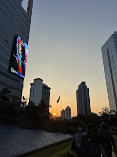 Wide shot of a large outdoor LED video display mounted on a building facade during sunset.
