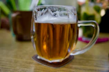 Close-up of a traditional ceramic beer mug filled with frothy beer on a rustic bar counter.