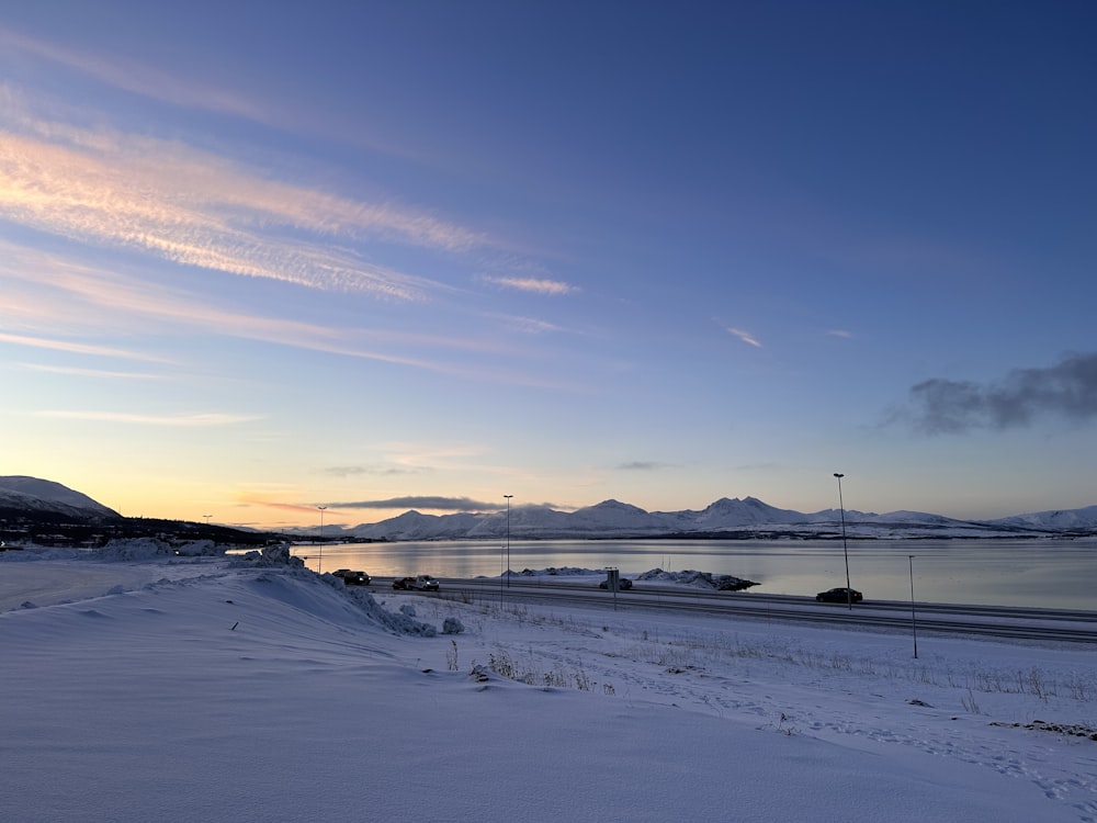 a snow covered field with a body of water in the distance