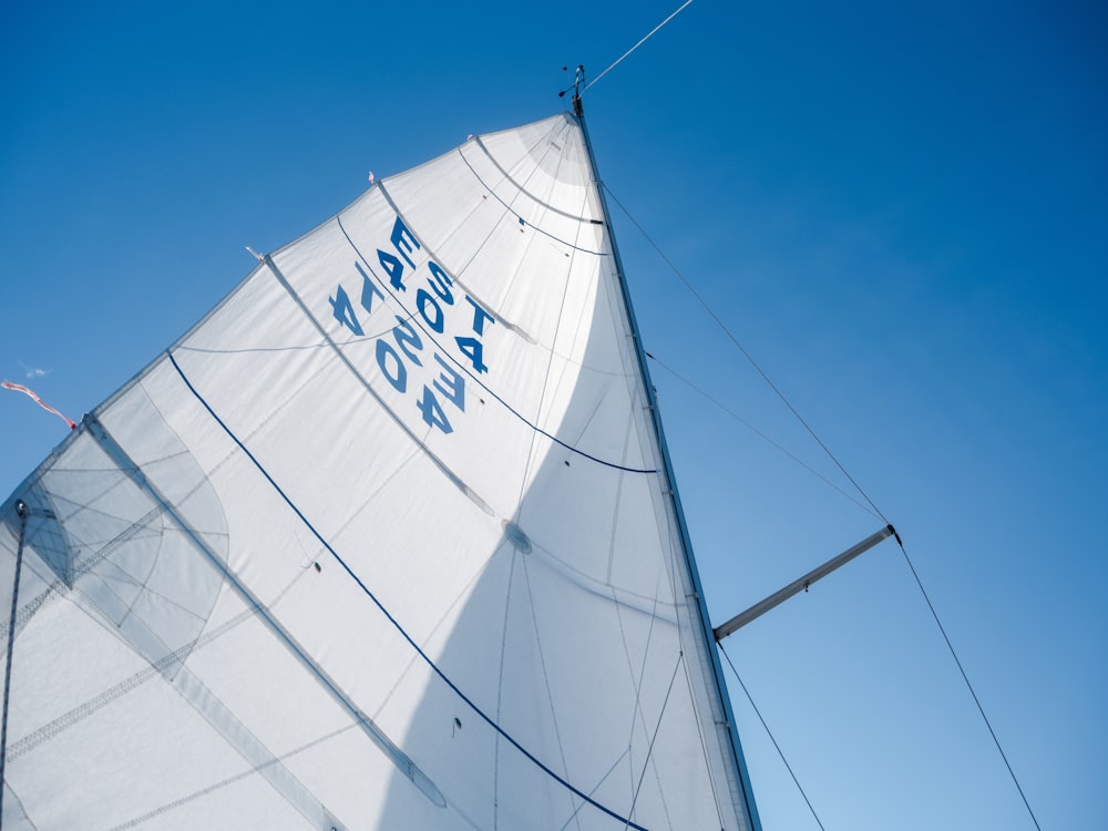 a white sail boat with a blue sky in the background