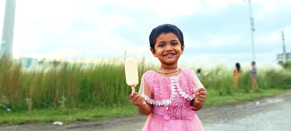a little girl in a pink dress holding a paddle