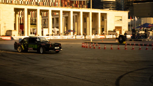 Fast-paced autocross event with cars weaving through tight cones on an urban course