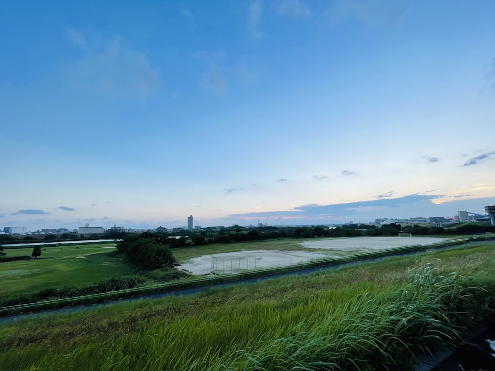 a grassy field with a lake in the background