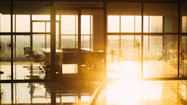 Sunlight streaming through large windows onto a sleek workspace with marketing materials.