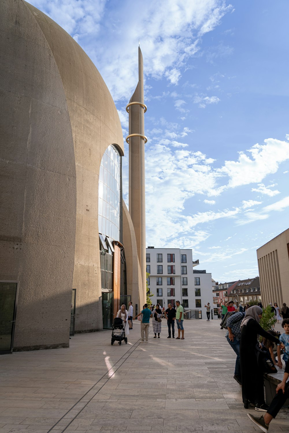 a group of people walking down a sidewalk next to a tall building