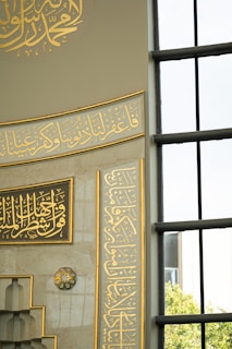 Elegant Arabic calligraphy adorning a mosque wall with gold leaf accents.