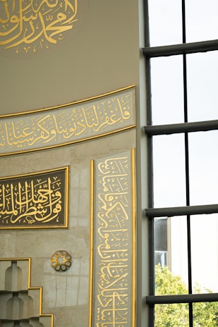 Elegant Arabic calligraphy adorning a mosque wall with gold leaf accents.