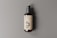 A dark amber glass pump bottle is positioned against a neutral gray background. The bottle features a cream-colored label with bold black text that reads 'PSD'. The pump on top is a matte black color, and the shadow cast suggests a light source from the left.