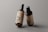Two amber glass pump bottles are placed against a neutral gray background. The bottles have a minimalistic label featuring the letters PSD and additional text, indicating they are mockup templates. The lighting highlights the glossy finish of the bottles, giving them a professional and sleek appearance.