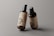 Two amber glass pump bottles are placed against a neutral gray background. The bottles have a minimalistic label featuring the letters PSD and additional text, indicating they are mockup templates. The lighting highlights the glossy finish of the bottles, giving them a professional and sleek appearance.