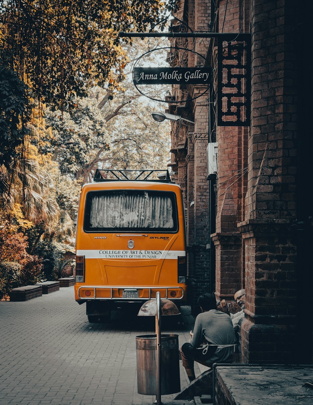an orange and white bus parked on the side of a road