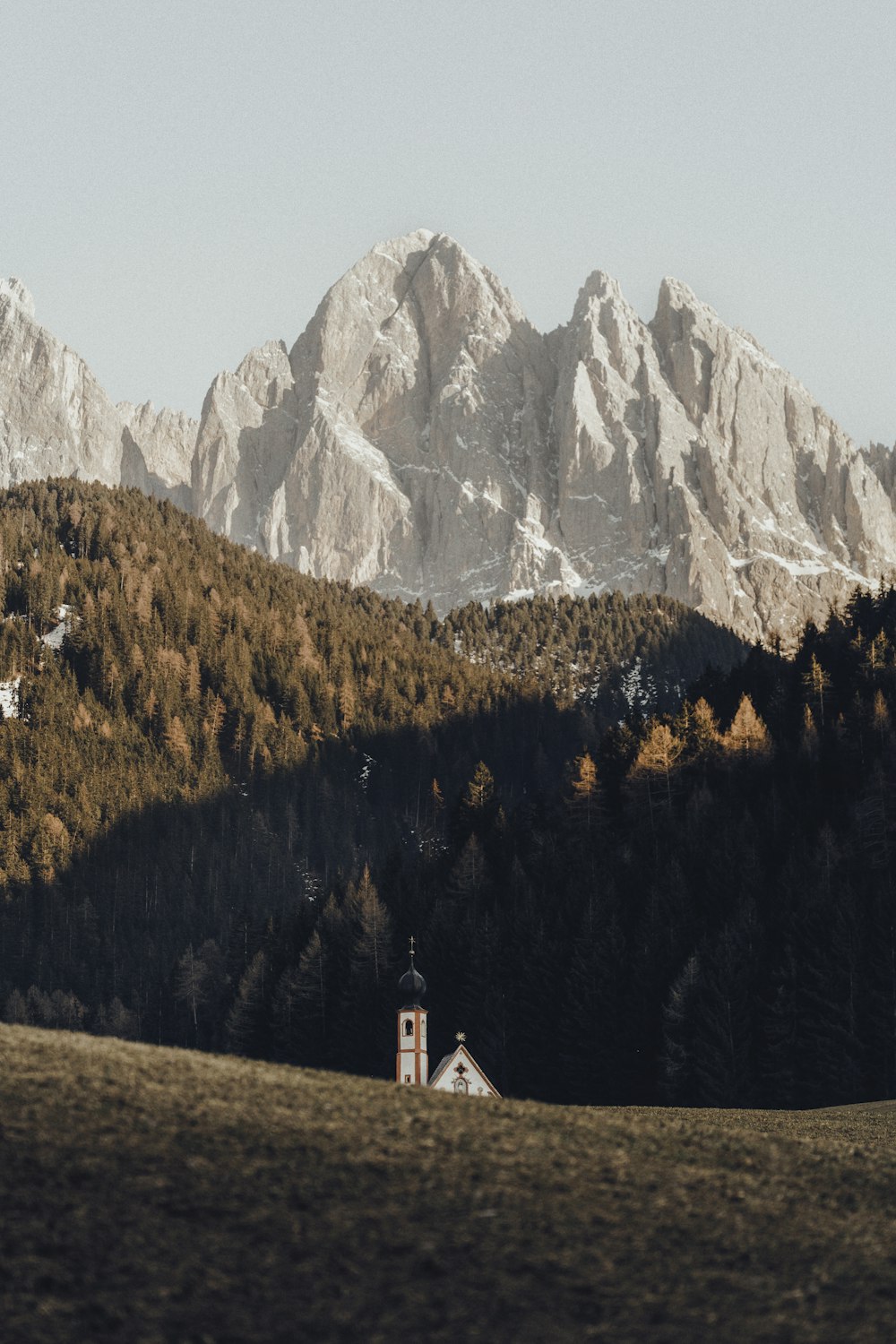 a church in the middle of a field with mountains in the background